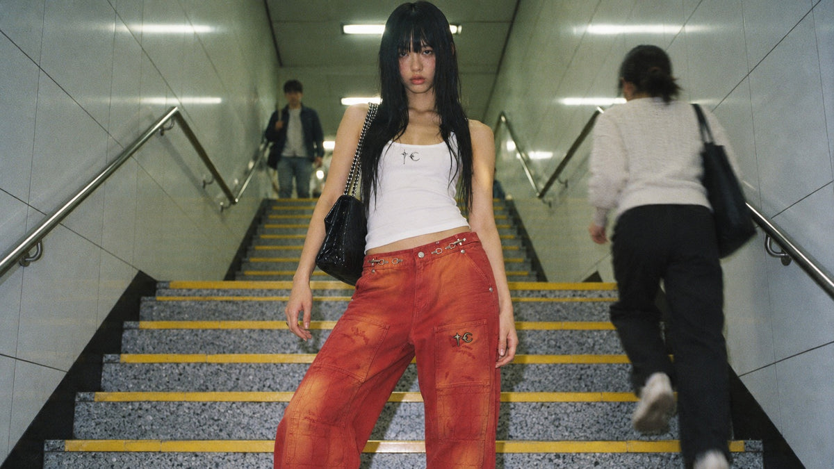Woman in black layered outfit standing on subway station stairs